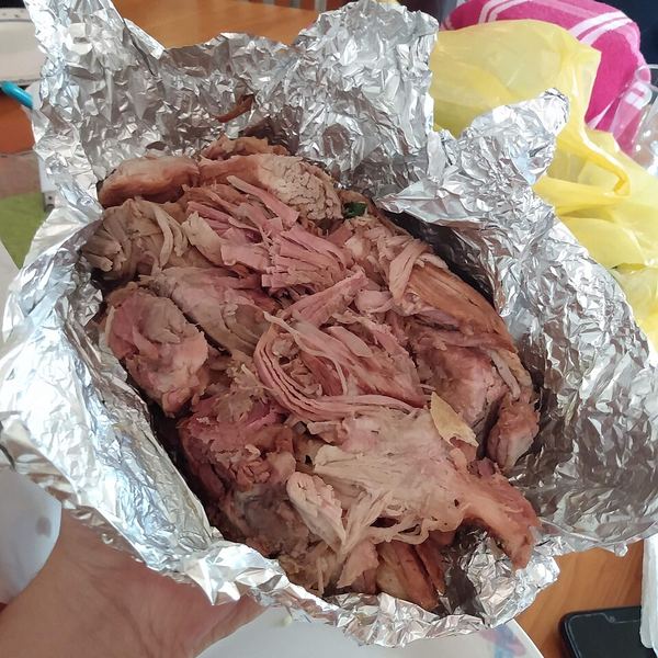 A kilo of shredded, pale cooked pork opened out on aluminium foil.