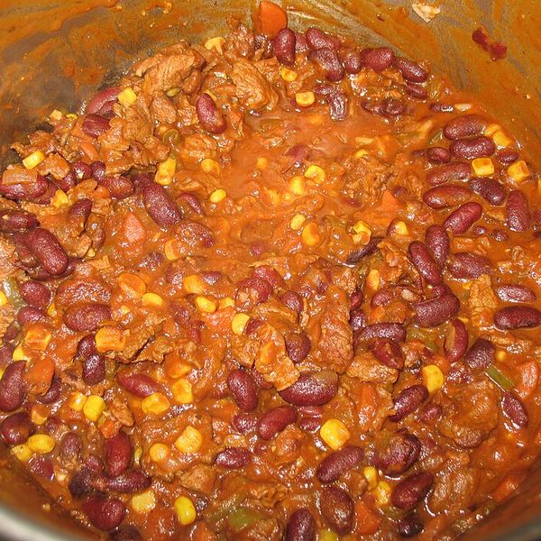 A pot of chili part-way through cooking, chile and aromatics already in with the browned meat.